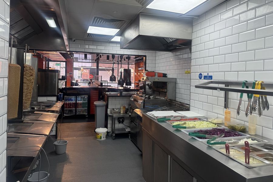 The kitchen line at German Doner Kebab: doner spits, fryers and the salad and sauce counter.