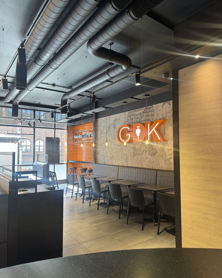 The dining area of a German Doner Kebab restaurant, with the orange GDK sign on the wall.