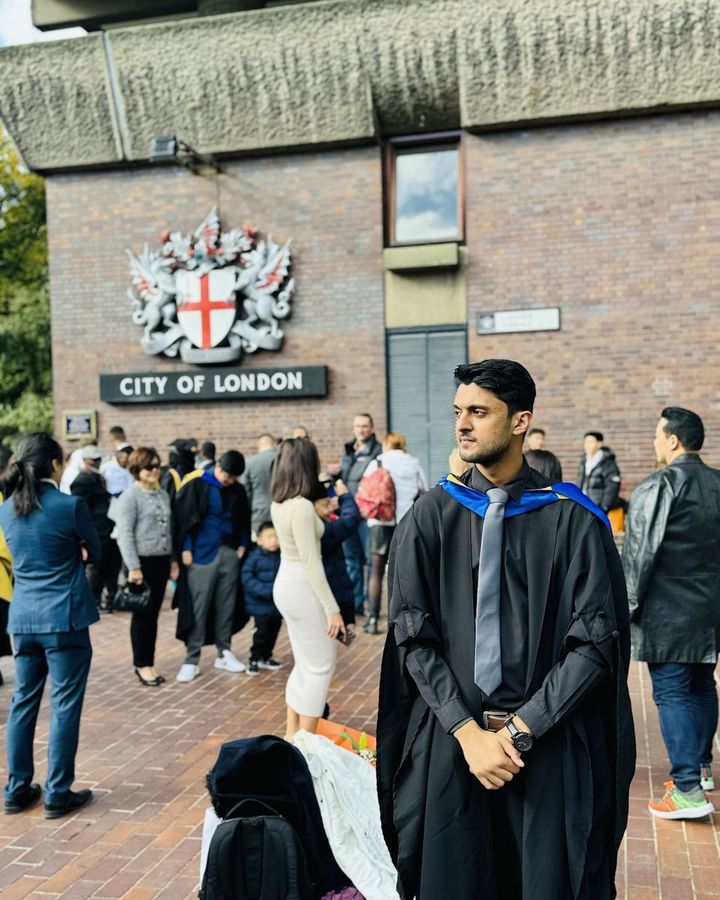 Muhammad in his graduation gown beneath the City of London crest.