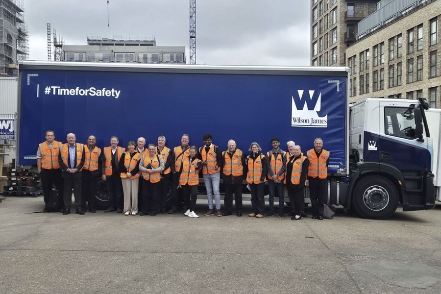 Muhammad with a CILT group in hi-vis in front of a Wilson James lorry at the Silvertown consolidation centre.